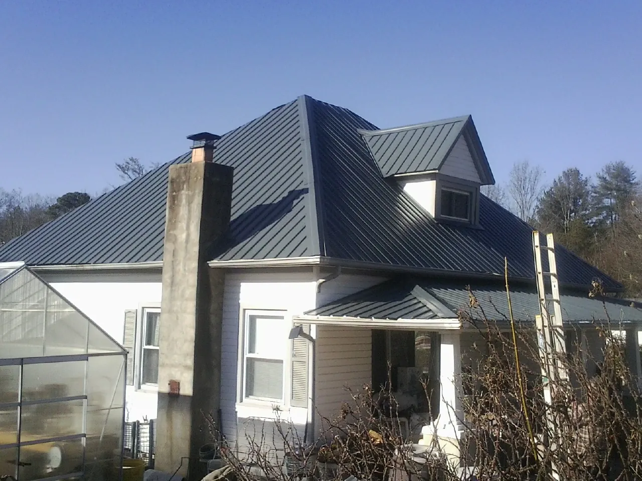 Dark blue standing seam metal roof on a white farmhouse with dormer — Slate & Tile Roof Repair by Roofing Brothers in Schuylkill Haven