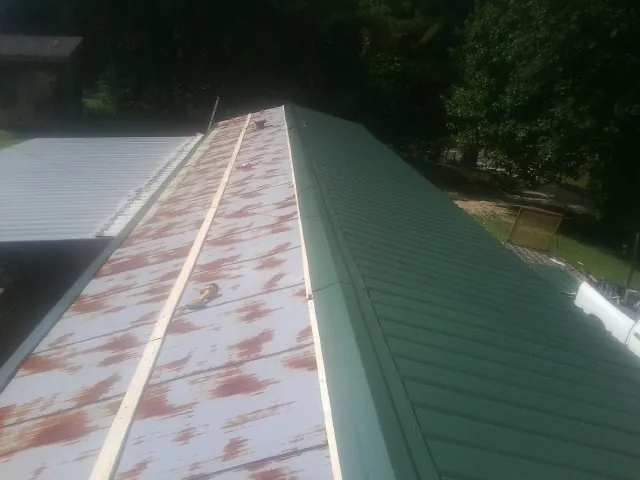 Old rusted panels beside newly installed green metal roofing — Wind Damage Roof Repair by Roofing Brothers in Schuylkill Haven