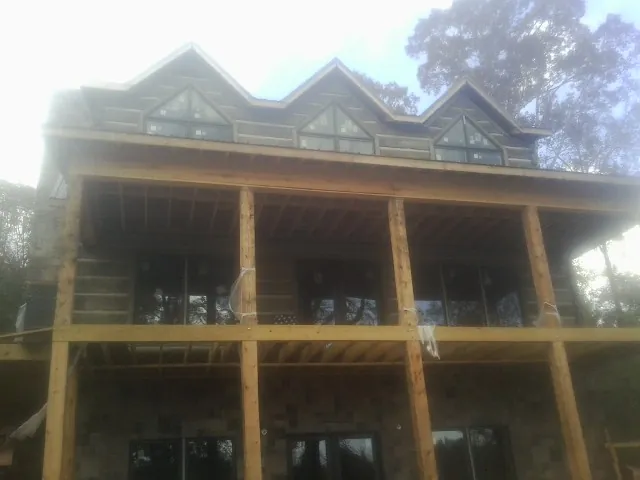 Dormers and porch framing on a large log home under construction — Roof Coating work by our crew in Schuylkill Haven