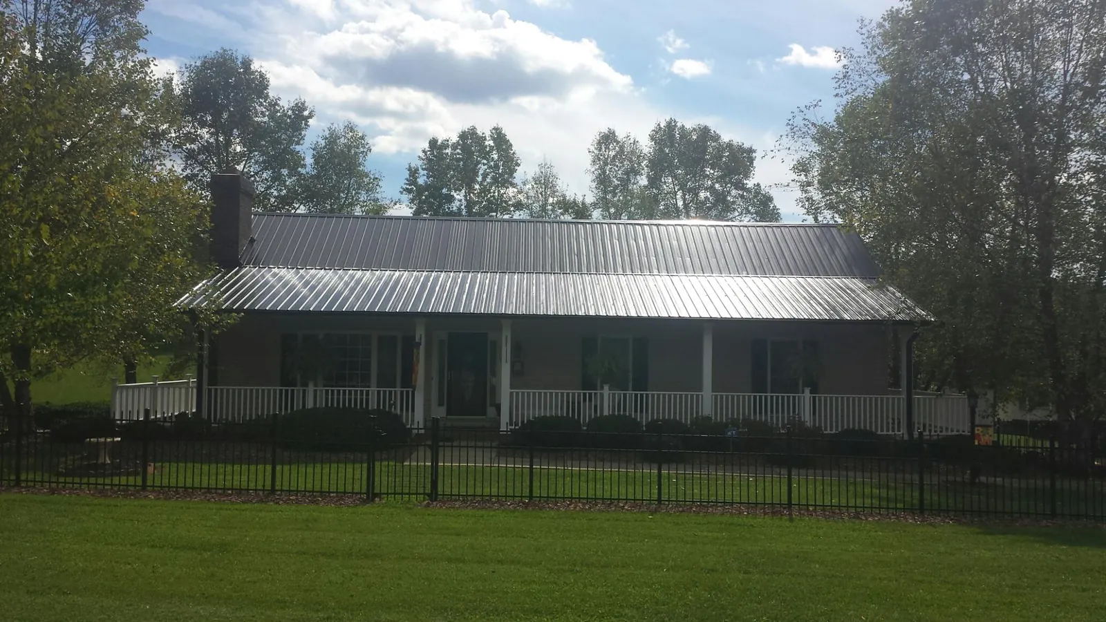 Gray metal roof on a brick ranch with a full width front porch — Gutter Guard Installation work by our crew in Schuylkill Haven