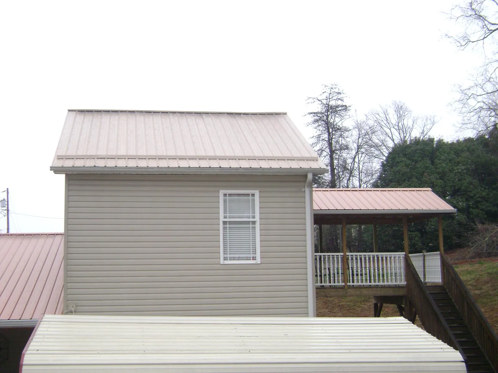 Tan metal roofs on a two story addition and attached porch, from a Roof Replacement job in Schuylkill Haven