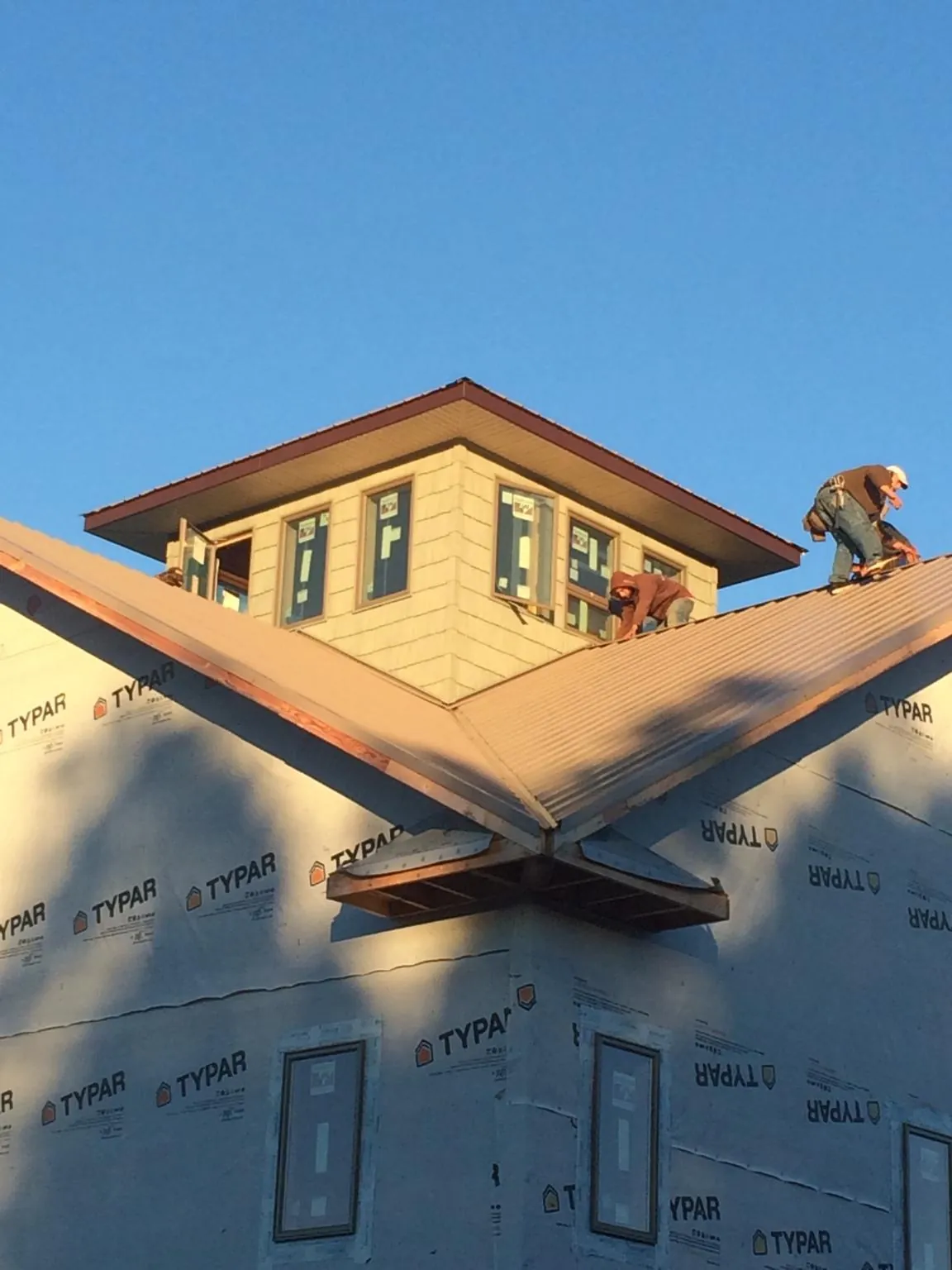 Roofers working around a rooftop cupola on a new metal roof at sunset — Roof Waterproofing in Schuylkill Haven by Roofing Brothers